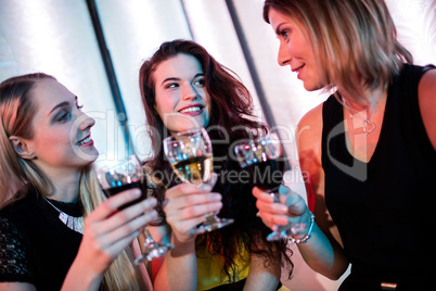 Smiling friends sitting together and having wine