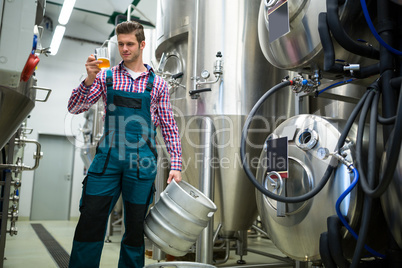 Brewer holding keg and testing beer