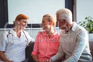 Nurse and senior couple sitting on a couch