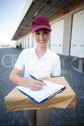 Portrait of delivery woman is holding a cardboard box and smilin