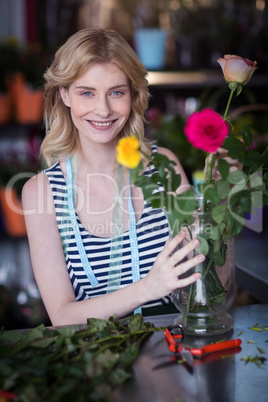 Smiling female florist arranging flower bouquet in vase at flowe