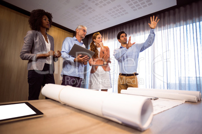 Man framing with hand while standing in board room with colleagu