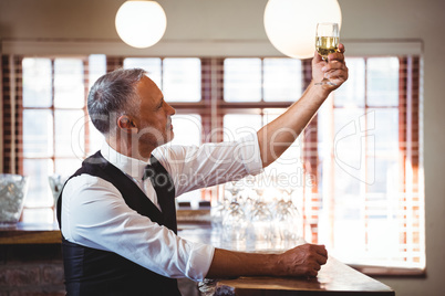 Bartender holding up a wine glass at bar counter