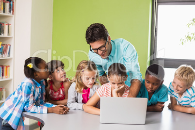 Teacher and kids using laptop in library