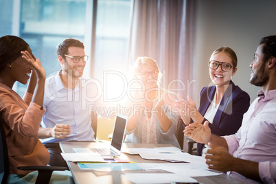 Coworkers applauding a colleague during a meeting
