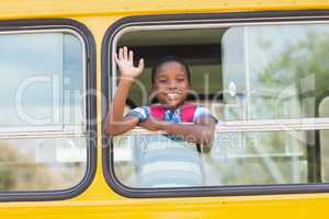 Portrait of schoolboy waving hand from bus