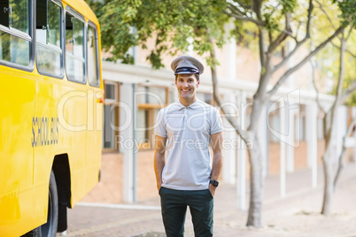 Smiling bus driver standing with hands in pocket in front of bus