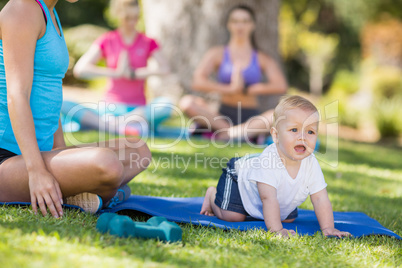 Woman exercising and her baby crawling