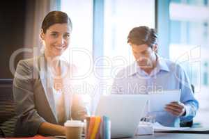 Businesswoman working on laptop with coworker