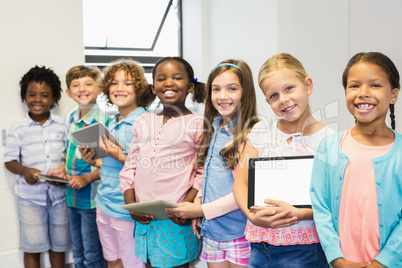 Portrait of students holding digital tablet in classroom