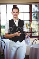 Portrait of waitress holding serving tray with champagne flutes&
