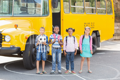 Smiling kids standing together in front of school bus