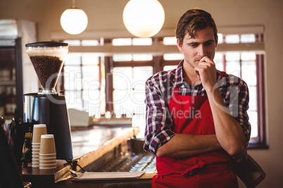 Thoughtful waiter standing at counter