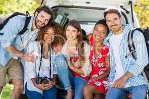Group of friends on trip sitting in trunk of car
