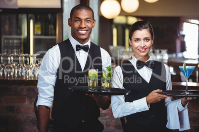 Waiter and waitress holding a serving tray with glass of cocktai