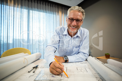 Architect working on blueprint at desk