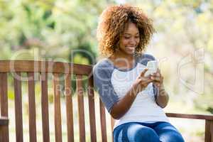 Woman using mobile phone while sitting on the bench
