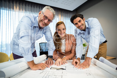 Businesswoman and coworker with blueprint on the desk