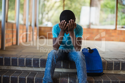 Sad schoolboy sitting alone on staircase