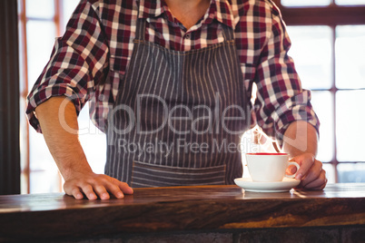 Mid section of waiter serving a cup of coffee