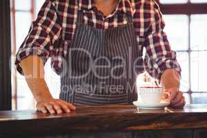 Mid section of waiter serving a cup of coffee