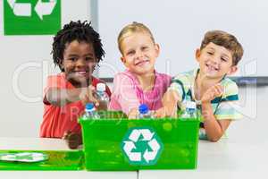 Kids holding recycled bottle in classroom