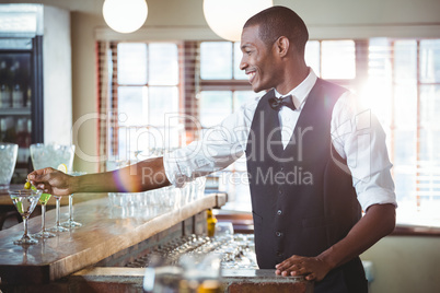 Bartender garnishing cocktail with olive