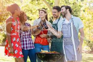 Group of friends toasting a beer bottle while preparing barbecue