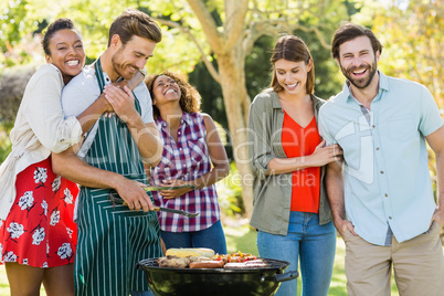 Happy friends preparing a barbecue grill in park