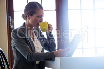 Woman drinking coffee and using tablet