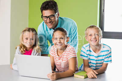 Teacher and kids using laptop in library