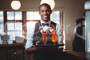 Bartender holding serving tray with two glass of cocktail