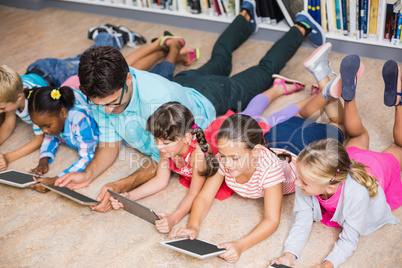 Teacher and kids using digital tablet in library
