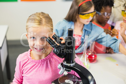 Schoolgirl holding microscope in laboratory