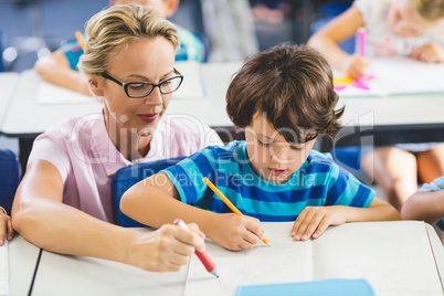 Teacher helping a boy with studies in classroom