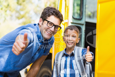 Smiling teacher and schoolboy showing thumbs up in front of scho
