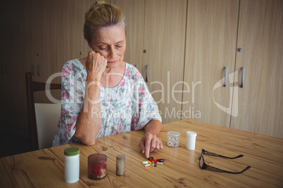 Worried senior woman with medics on the table