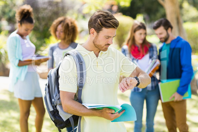 College boy checking time with the friends in background