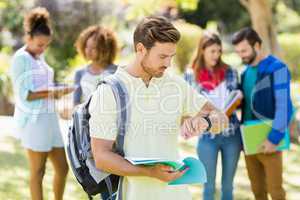 College boy checking time with the friends in background