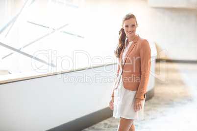 Beautiful young businesswoman standing in office corridor