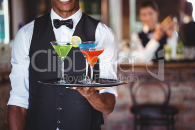 Bartender holding serving tray with cocktail glasses