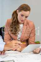 Businesswoman interacting with coworker using digital tablet