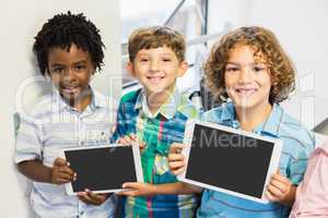 Portrait of students holding digital tablet in classroom