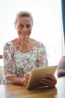 Senior woman looking at the camera using a digital tablet