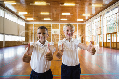 Smiling boys showing thumbs up in school gym