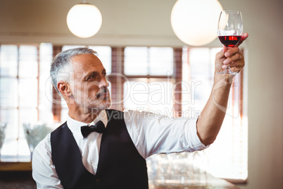 Bartender holding up a wine glass at bar counter