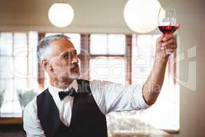 Bartender holding up a wine glass at bar counter