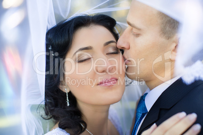 the groom gently embraces and kisses the bride