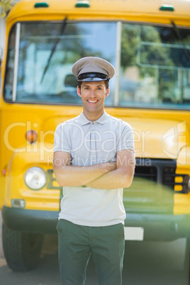 Smiling bus driver standing with arms crossed in front of bus