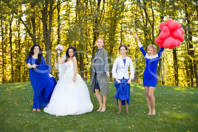 Bride with her friends dancing in the meadow